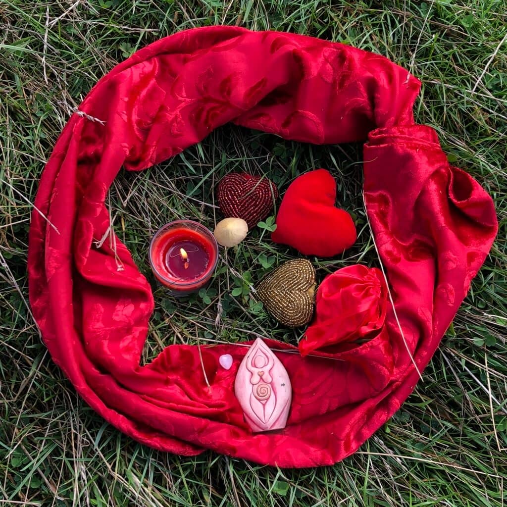 Roter Stoff und Herzen auf Gras mit Kerze