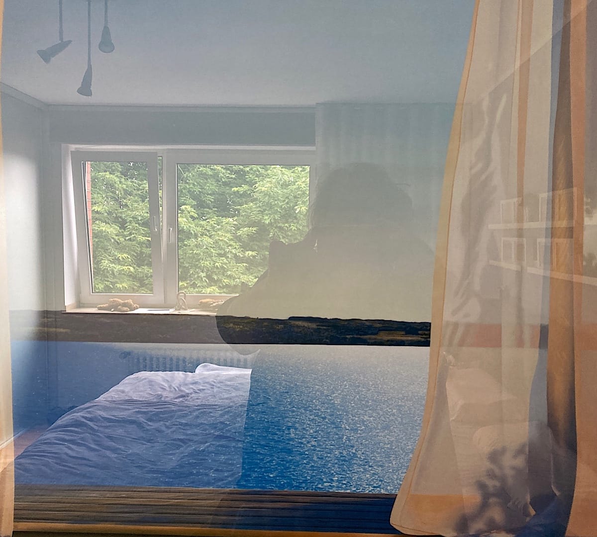 Modernes Schlafzimmer mit großem Fenster und Blick auf Bäume
