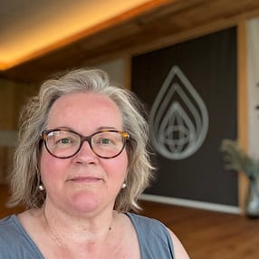 img 2025 09 13 150627 Birgit Nora Schäfer vor einem Yoga-Bild in einem Yoga-Raum