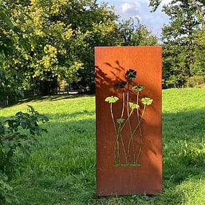 img_2484.jpg Rostige Metallplatte mit Blumenmotiv im Grünen