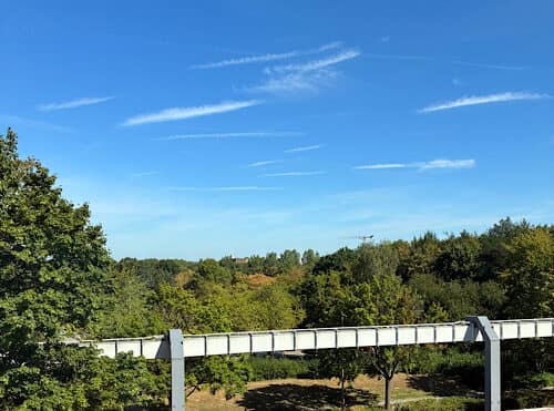 img 2025 09 13 145811 Weiße Hochbahn vor grüner Parklandschaft unter blauem Himmel