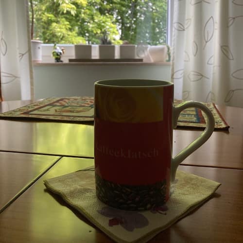 Roter Kaffeetasse auf Tisch vor Fenster