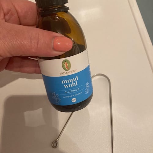 Hand hält Flasche Mundspülung auf weißer Oberfläche