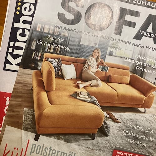 img_2316.jpg Frau sitzt lächelnd auf einem braunen Sofa