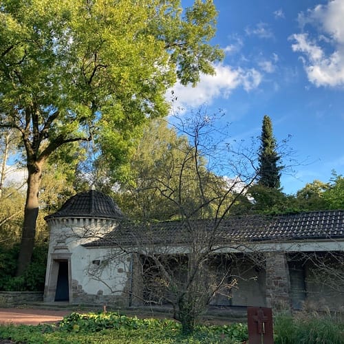img_2649.jpg Historisches Gebäude umgeben von grünen Bäumen und Sträuchern