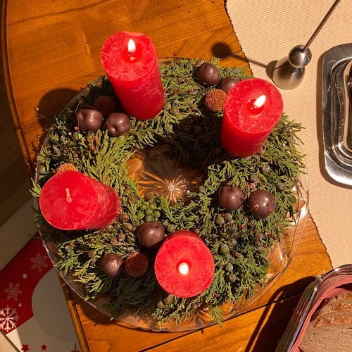img_3065.jpg Adventskranz mit brennenden roten Kerzen auf Tisch