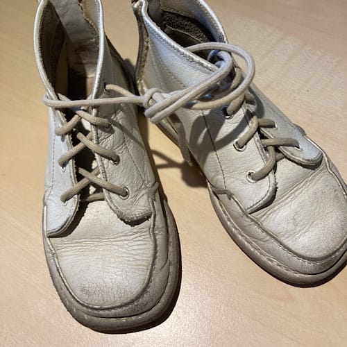 img_3243.jpg Abgenutzte weiße Schnürschuhe auf Holztisch
