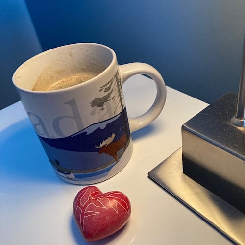 Tasse mit Kaffe, Lampe und rotes Herz auf Tisch