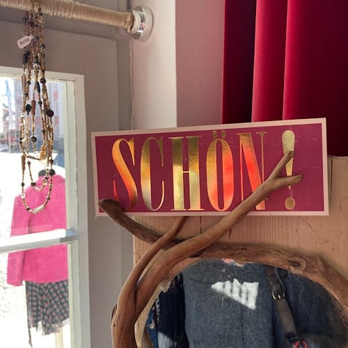 img_3642.jpg Schild ‚Schön‘ auf einem Holzast in sonnigem Schaufenster