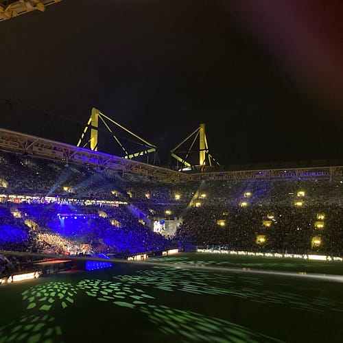 208069B3-EA88-4E27-BFE9-0715F231DD19 Beleuchtetes Stadion bei Nacht mit Menschenmenge