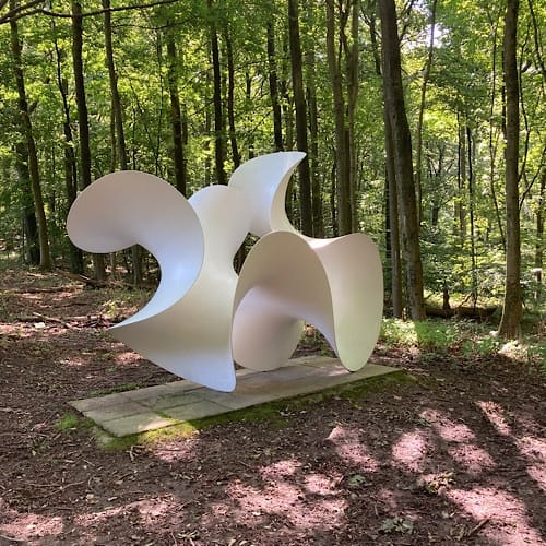 Abstrakte weiße Skulptur im grünen Wald