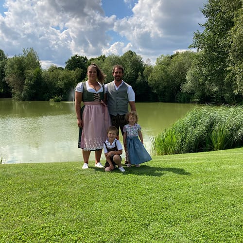 Die 4-köpfige Familie meines Sohnes mit seiner Frau und seinen beiden Kindern in Trachtenkleidung vor einem Teich bei einer Hochzeitsfeier