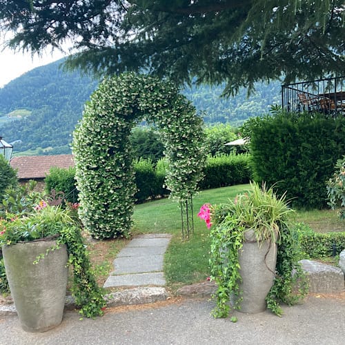 Grüner Bogengang mit Blumentöpfen in Berglandschaft bei Schloß Plars in Algund