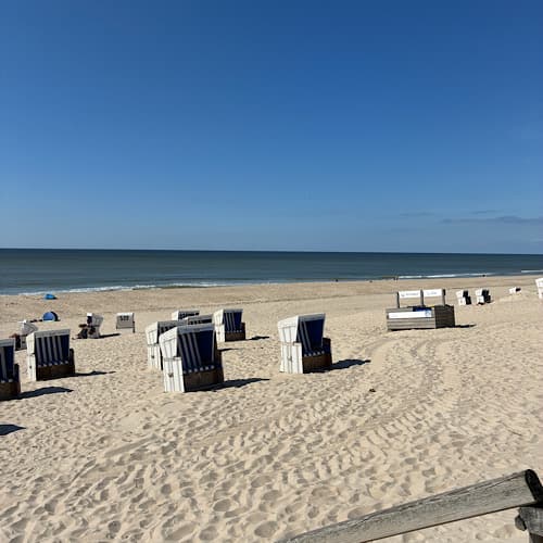 Strandkörbe am sonnigen Sandstrand mit blauem Himmel