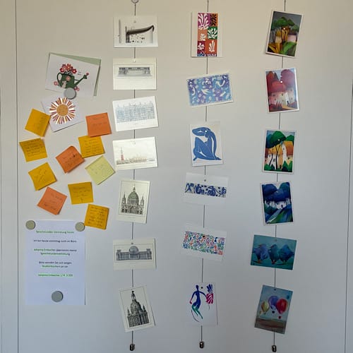 img 2025 09 13 151130 Hängende Grußkarten, Illustrationen und Notizzettel an weißer Wand