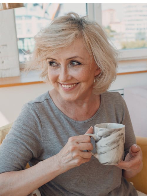 Lächelnde ältere Frau hält eine Kaffeetasse