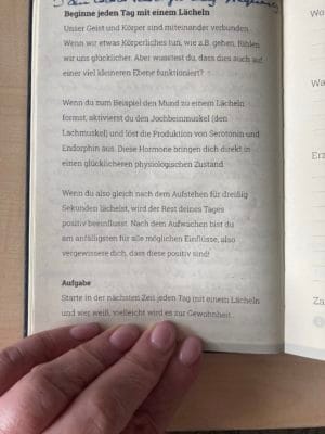 img_3050.jpg Hand hält ein offenes Buch auf Deutsch