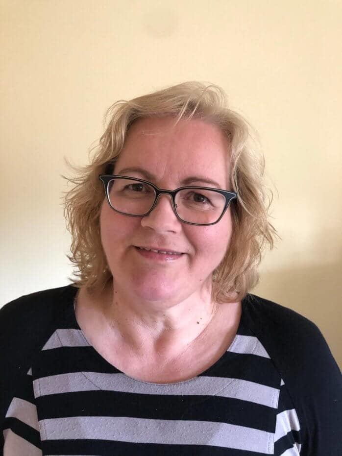 Frau mit Brille und gestreiftem Oberteil lächelt