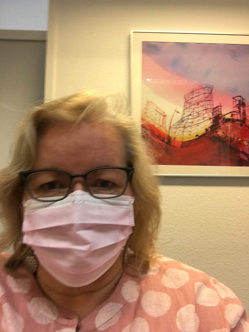 Frau mit Maske vor abstraktem Kunstwerk